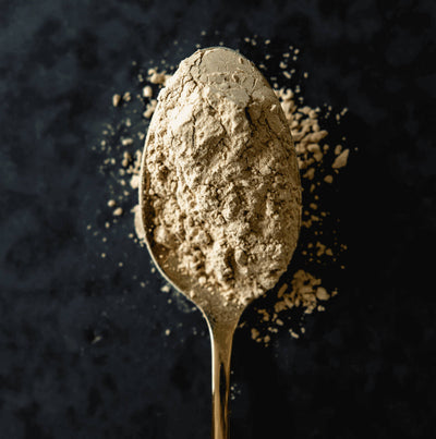 An overhead shot of a pile of Ashwagandha powder on a golden spoon.